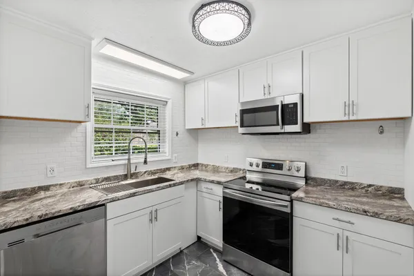 a kitchen with stainless steel appliances granite countertop a sink a stove a microwave and wooden cabinets
