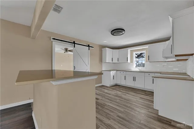 a kitchen with stainless steel appliances granite countertop a sink a stove and white cabinets with wooden floor