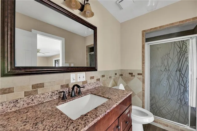 a bathroom with a granite countertop sink a toilet and a mirror