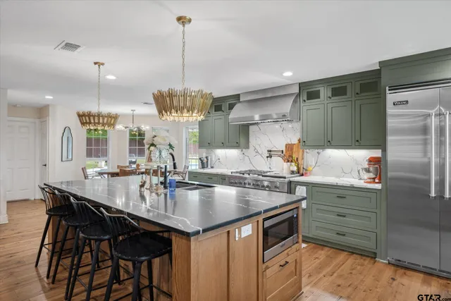 a kitchen with stainless steel appliances granite countertop a sink a stove and a wooden floors