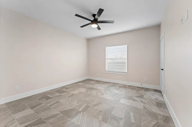 an empty room with a ceiling fan and window