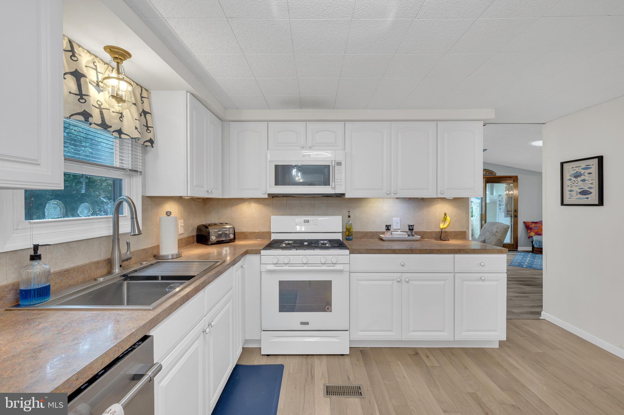 30879 Maplewood Road Ocean View, DE 19970 - Photo 20 of 41 a kitchen with granite countertop white cabinets and white appliances