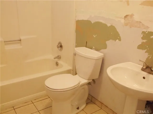 a white toilet sitting next to a bathroom sink and a tub
