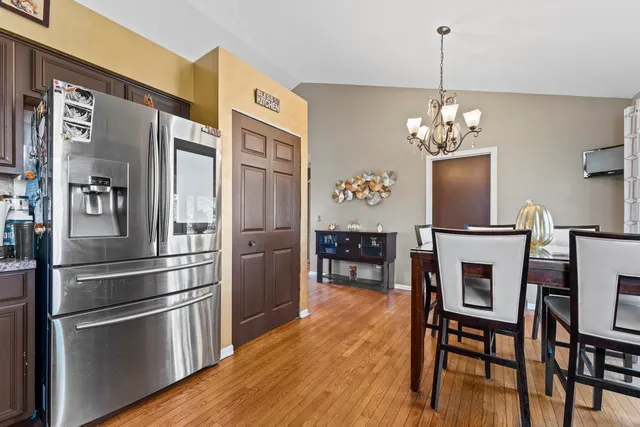 a kitchen with stainless steel appliances kitchen island granite countertop a refrigerator a stove a microwave oven a dining table and chairs with wooden floor