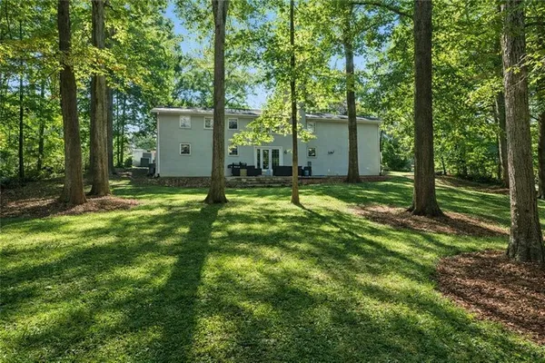 a backyard of a house with lawn chairs and a large tree