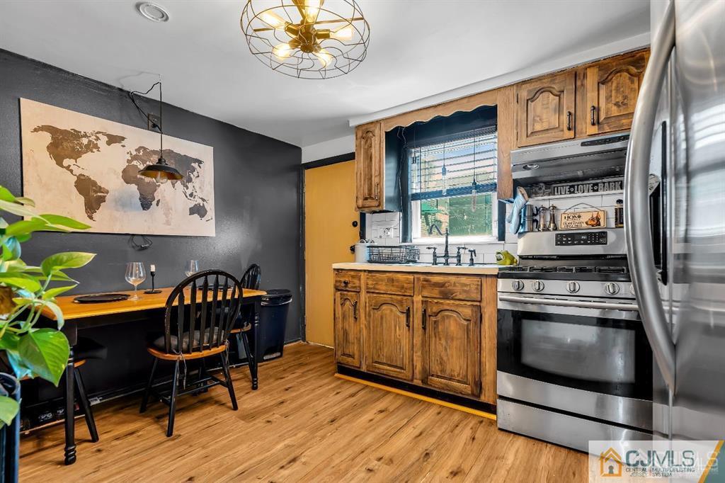 7 Downing Street Newark, NJ 07105 - Photo 6 of 18 a kitchen with stainless steel appliances granite countertop a stove top oven a dining table and chairs with wooden floor