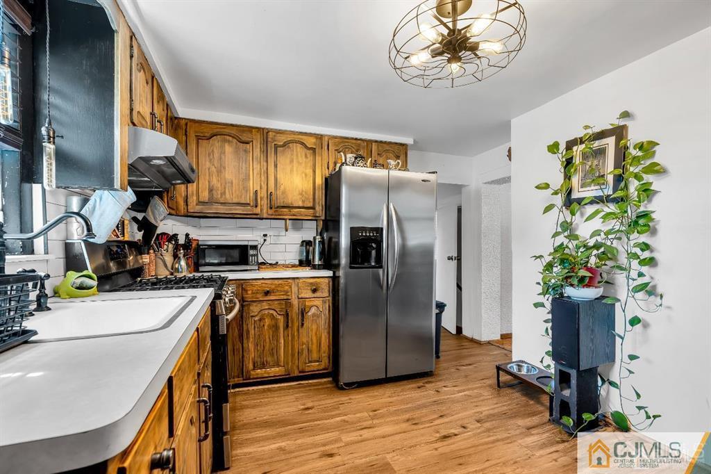 7 Downing Street Newark, NJ 07105 - Photo 8 of 18 a kitchen with stainless steel appliances granite countertop a refrigerator a sink dishwasher and white cabinets with wooden floor