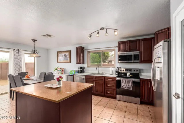 a kitchen with stainless steel appliances granite countertop a sink a stove and a refrigerator