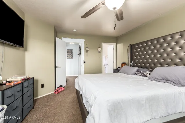 a bed room with a bed mirror tv on desk and a window