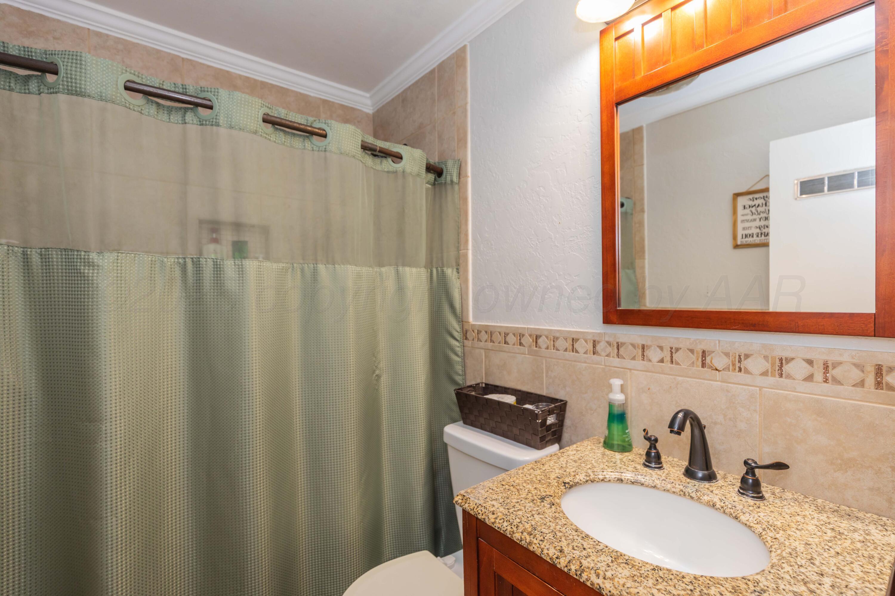 1208 Pecan Street Amarillo, TX 79107 - Photo 19 of 34 a bathroom with a granite countertop sink vanity mirror and shower