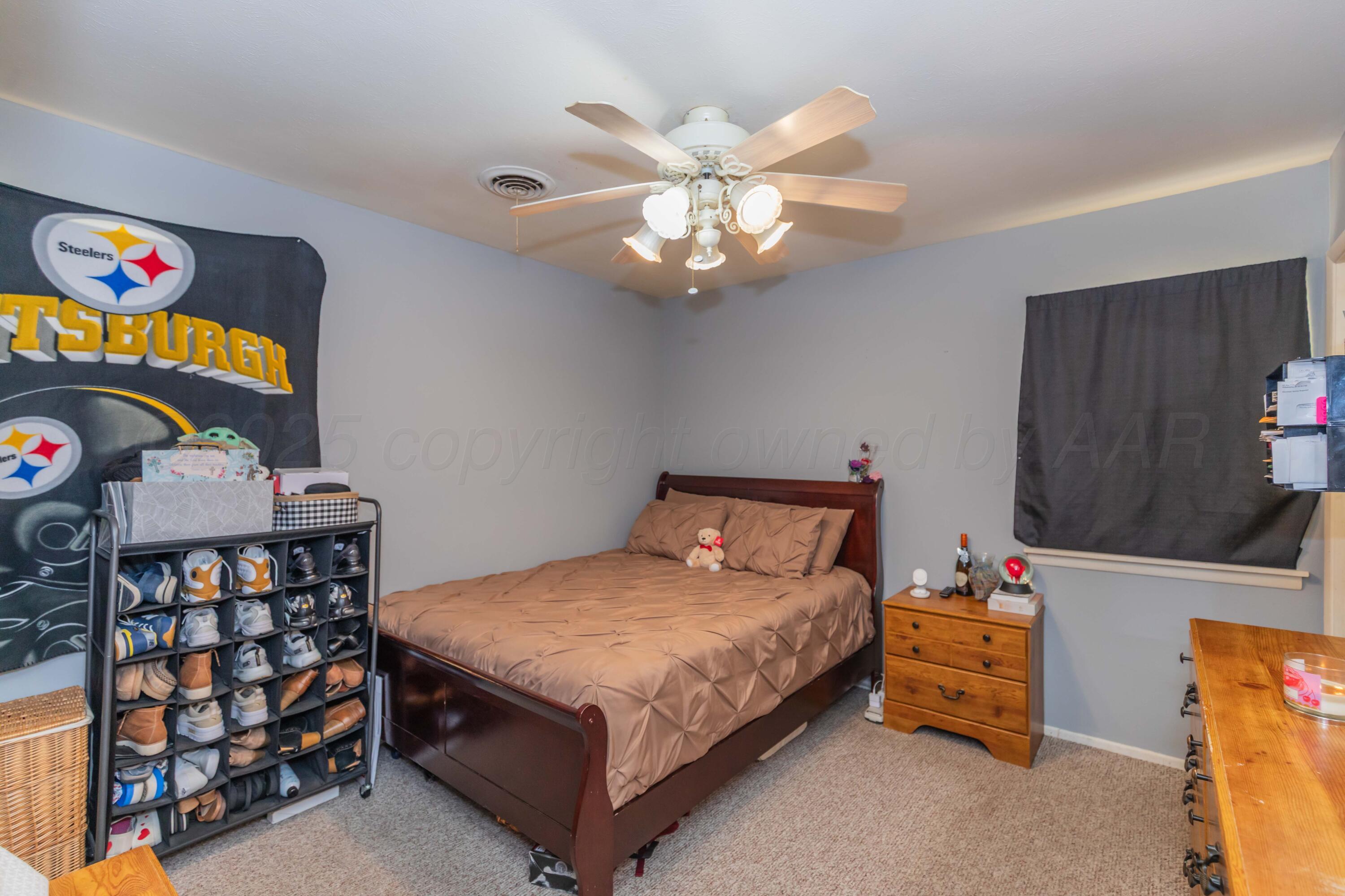 1208 Pecan Street Amarillo, TX 79107 - Photo 27 of 34 a bedroom with a bed and a bookshelf with wooden floor
