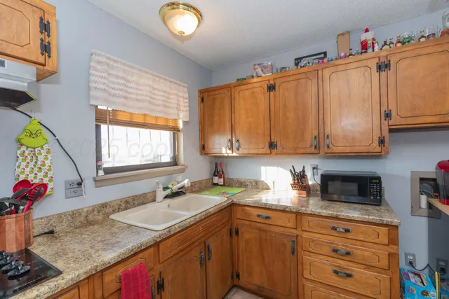 a kitchen with granite countertop a sink cabinets stainless steel appliances and a window