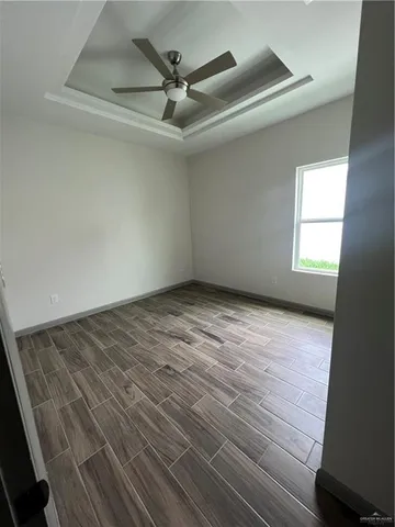 an empty room with wooden floor fan and windows