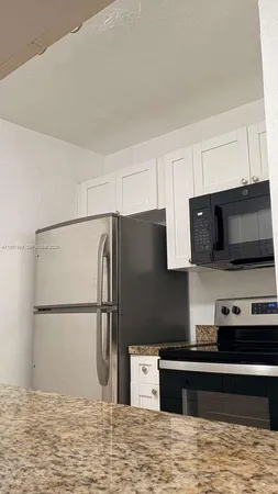 a kitchen with granite countertop white cabinets and a sink