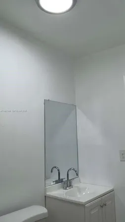 a white toilet sitting next to a bathroom sink and vanity