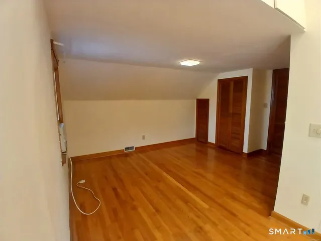 an empty room with wooden floor and bathroom