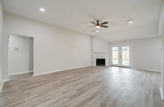 an empty room with wooden floor fireplace and fan