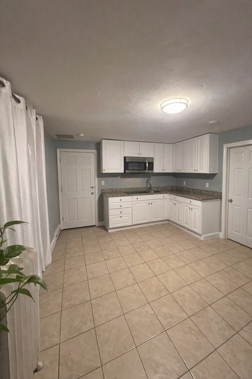 178 Cohasset Street, Unit 1 Worcester, MA 01604 - Photo 4 of 7 a large white kitchen with cabinets and a refrigerator