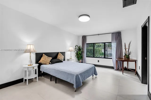 a bedroom with a bed lamp and a large window