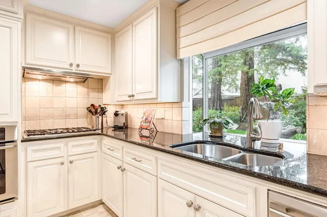 a kitchen with stainless steel appliances white cabinets a window and a sink