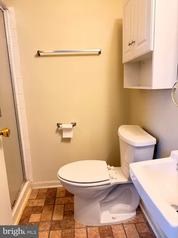 a white toilet sitting next to a bathroom sink and a shower