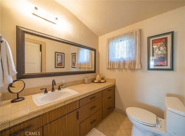 a bathroom with a granite countertop toilet sink and mirror