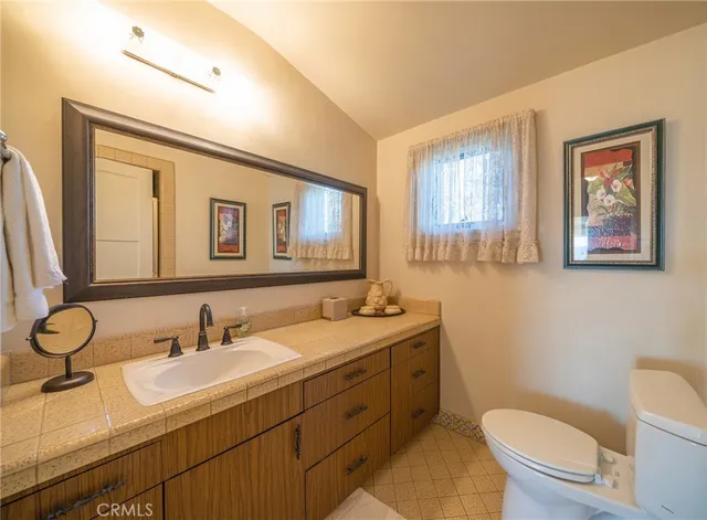 a bathroom with a granite countertop toilet sink and mirror