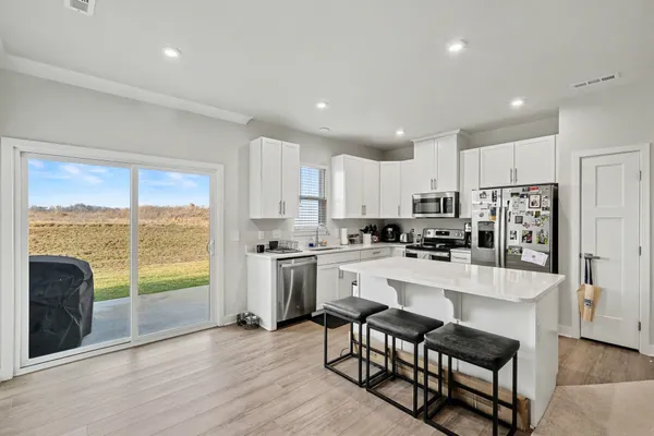 a kitchen with stainless steel appliances granite countertop a stove a refrigerator a sink a stove and white cabinets with wooden floor