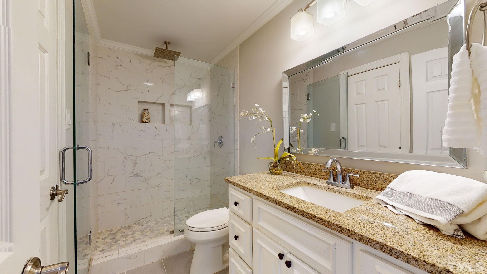 1613 Jenks Carpenter Road Cary, NC 27519 - Photo 44 of 60 a bathroom with a granite countertop sink a toilet and shower