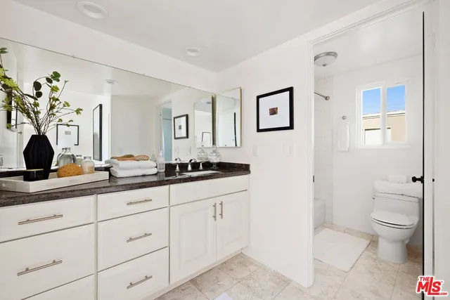 a bathroom with a granite countertop sink a toilet and a mirror