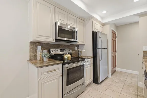 a kitchen with stainless steel appliances white cabinets white stove a microwave and a refrigerator