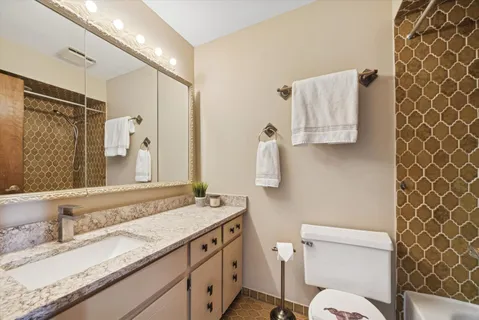 a bathroom with a granite countertop sink toilet and shower