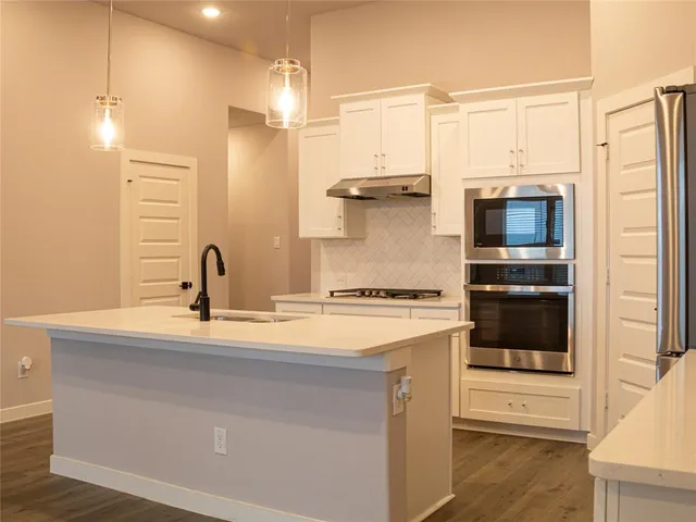 a kitchen with a sink and a stove top oven with wooden floor