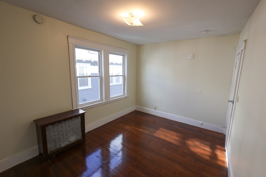 144 Blake Street, Unit 2 Boston, MA 02136 - Photo 17 of 28 an empty room with wooden floor and windows