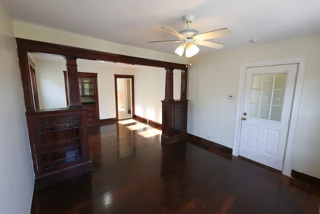 an empty room with wooden floor fan and windows