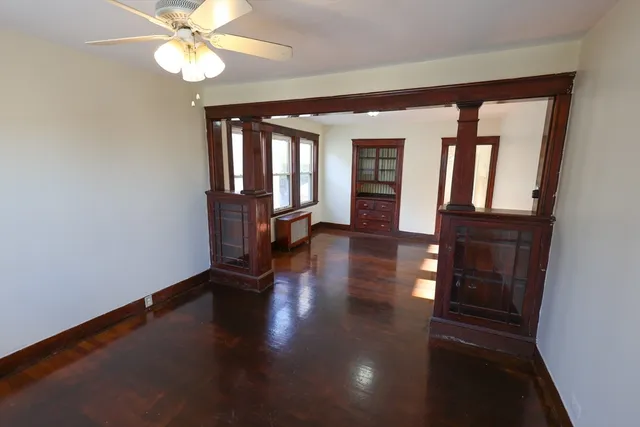 an empty room with wooden floor fan and windows