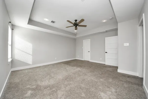 an empty room with a ceiling fan and carpet