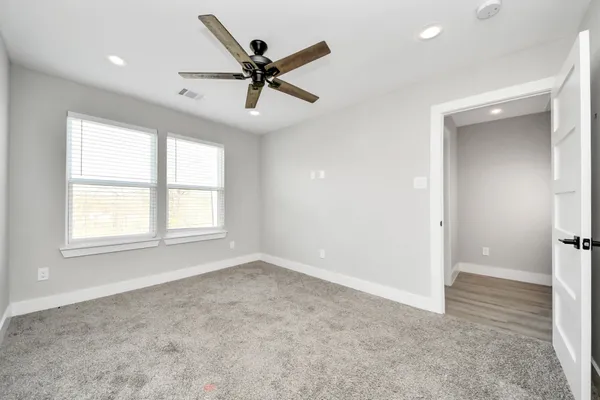 an empty room with windows and fan