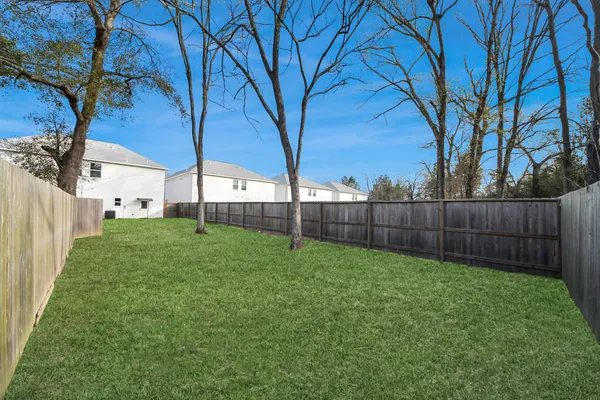 a view of a backyard with large trees and wooden fence