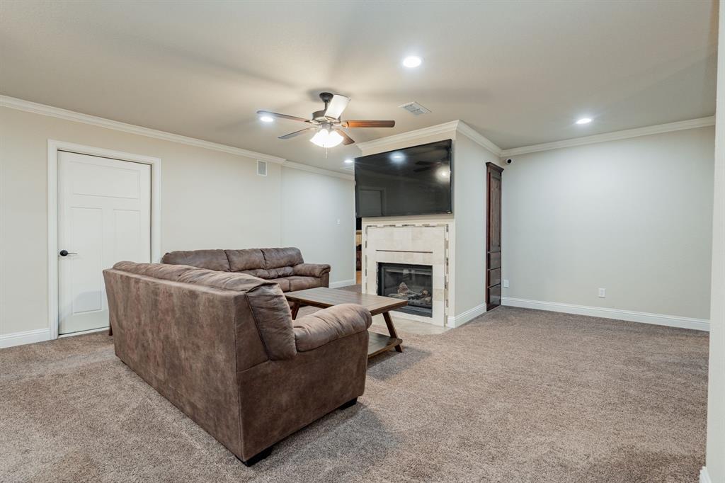 2687 McClendon Road Weatherford, TX 76088 - Photo 24 of 40 a living room with furniture a fireplace and a flat screen tv