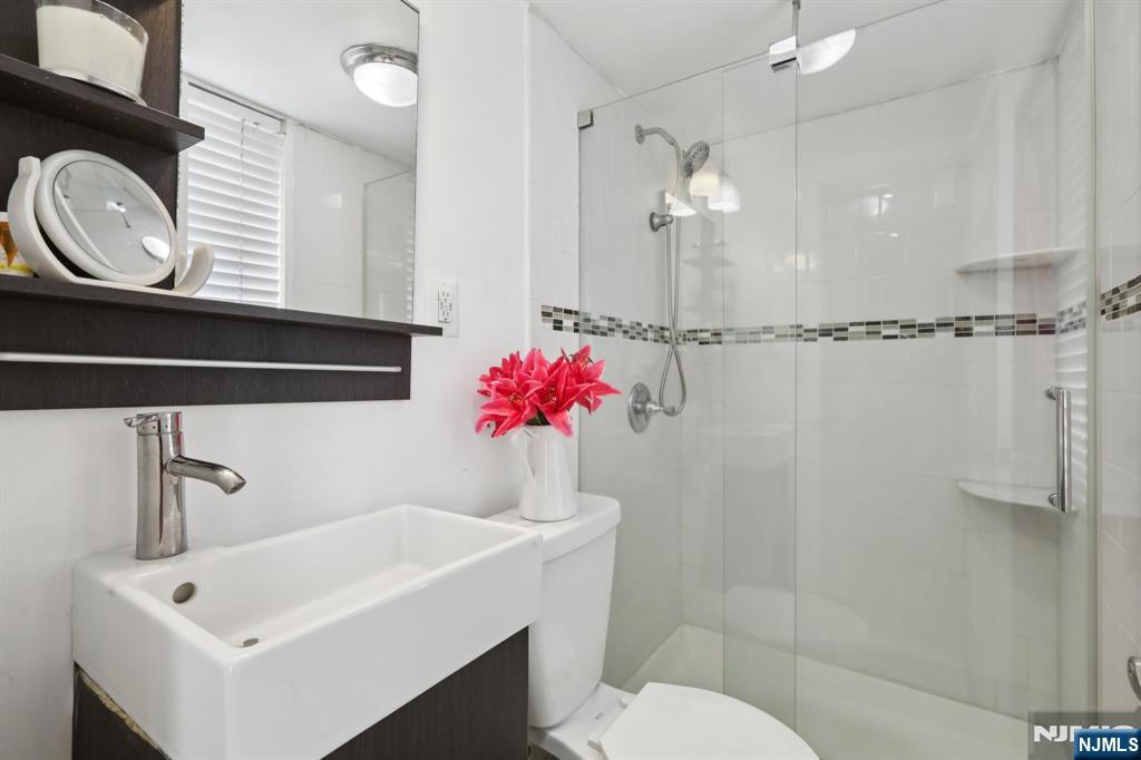 150 Overlook Avenue, Unit 7F Hackensack, NJ 07601 - Photo 17 of 24 a bathroom with a sink a toilet and a mirror