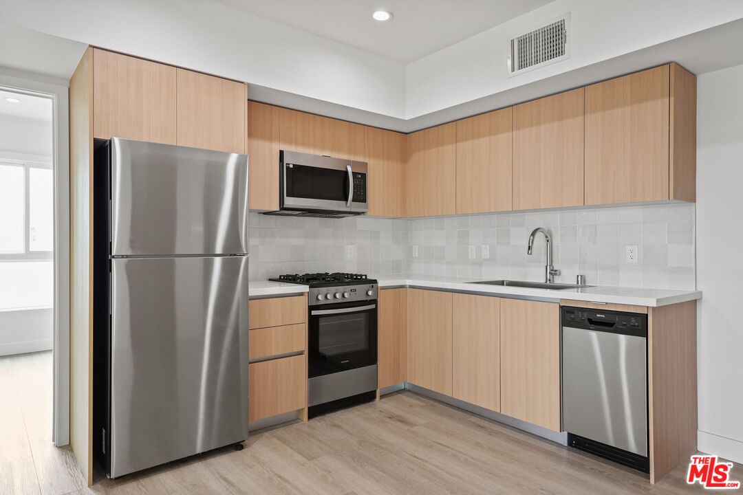 1600 Venice Blvd., Unit 102 Venice, CA 90291 - Photo 7 of 15 a kitchen with stainless steel appliances granite countertop a refrigerator stove top oven and sink