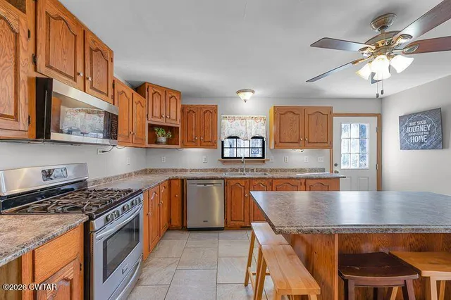 a kitchen with stainless steel appliances granite countertop a stove top oven a sink dishwasher and cabinets with wooden floor