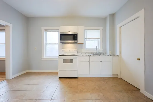 a kitchen with granite countertop white cabinets and white appliances