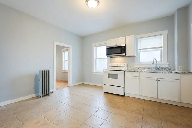 a kitchen with granite countertop a stove top oven sink and cabinets