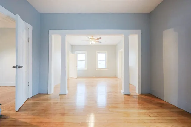 a view of an empty room with wooden floor and a window