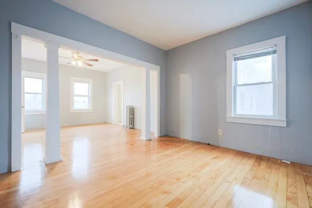 a view of an empty room with wooden floor and a window