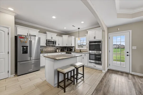 a kitchen with stainless steel appliances kitchen island granite countertop a refrigerator and microwave