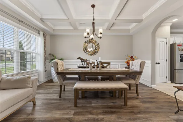 a dining room with wooden floor a chandelier a wooden table and chairs