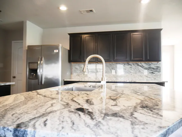 a kitchen with granite countertop a stove a refrigerator and a sink
